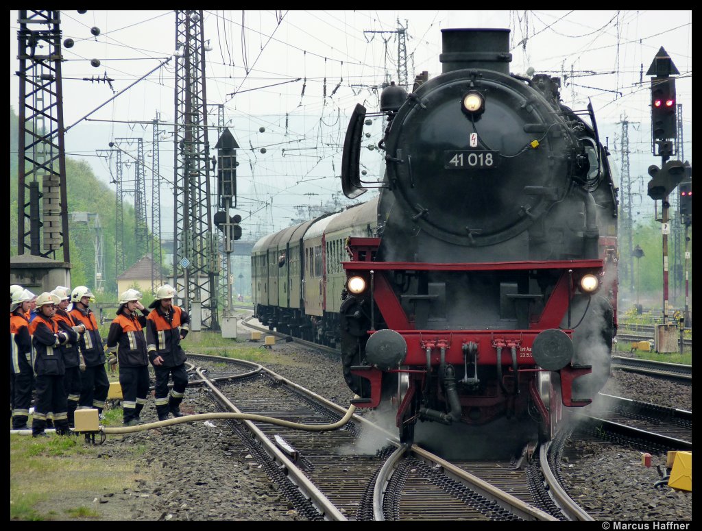 Am 1. Mai 2010 fuhr die 41 018 der Dampflok-Gesellschaft Mnchen (DGM) mit dem Zug der Frnkischen Museums-Eisenbahn (FME) nach Bebra zum dortigen Dampfloktreffen. Eigentlich sollte an dem Zug die 52 8195-1 der FME hngen, doch die war zu Kesselreperatur im AW Meiningen. Das Team der 41 018 lie noch etwas besonderes einfallen: Sie montierten die Fnfton-Pfeife der 10 002 an die 41 018, somit hatte die Lok einen sehr gewhnungsbedrftigen Pfiff. Eine Fnfton-Pfeife hrt sich m.M. an wie eine amerikanische Pfeife, ein tiefer, satter Ton. Das Bild entstand bei nicht so optimalen Fotowetter beim Wasserfassen in Gemnden am Main vom Bahnsteig-Ende aus.