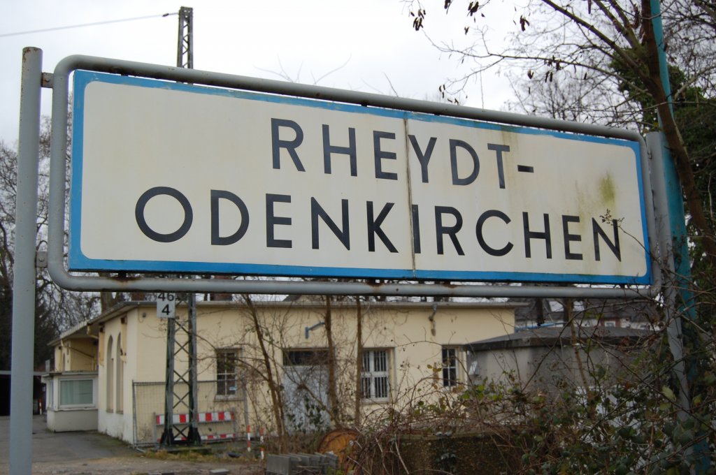 Bahnhofsschild Rheydt-Odenkirchen im Hintergrund sieht man die Reste des ehemals stolzen Bahnhofsgebudes. Einst waren zwei Stockwerke auf dem Stumpf, doch was von Zeiten Weltkrieg brieg blieb, verfllt jetzt mit den Jahren. Vor dem zweigte hier die Strecke von Odenkirchen nach Mnchengladbach ab, die sich in der Gegenrichtung in Hochneukirch weiter nach Jlich verzweigte. Auch ging von Odenkirchen die Gterzugstrecke nach Rheydt Verschiebebahnhof ab, die auch dem Zweiten Weltkrieg zum Opferfiehl. Was einem ein Schild alles erzhlen kann........12.1.2008