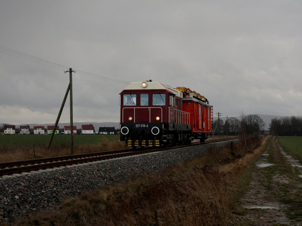 Die 107 018 am 10.12.2011 mit einem Oberleitungsmontierwagen unterwegs bei Petriroda.