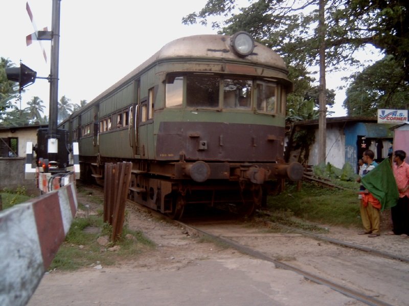 Die Schnellbahn von Colombo nach Galle (Sri Lanka) fotografiert am 28.11.2004 (4Wochen vor dem Tsunami der diese Bahn wegsphlte).
Aufgenommen im Ort Betona an einem Bahnbergang der mit der grnen Flagge des Wrters gesperrt wrde.