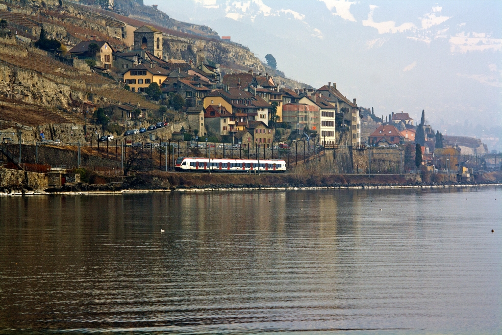 Ein Stadler FLIRT  RABe 523 er der SBB (RER Vaudois) als S1 (Villeneuve - Montreux -  Vevey - Lausanne -  Yverdon-les-Bains), passiert am 26.02.2012 St Saphorin, am Ufer des Lc Leman, er fhrt in Richtung Lausanne.