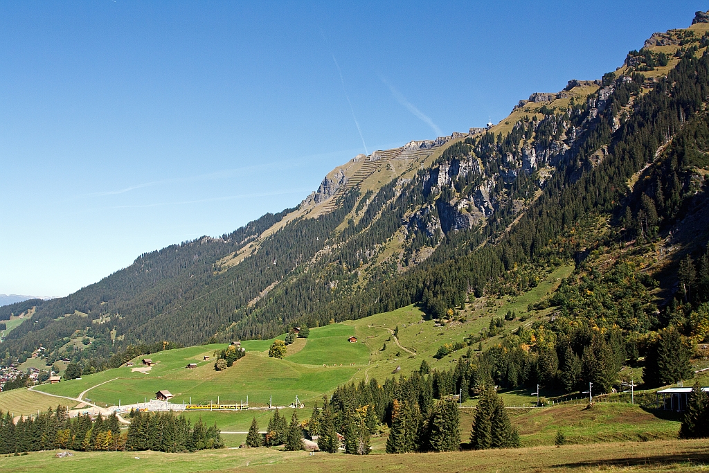 Ein Zug-Such-Bild vom einem schnen Schweizer Weekend: Ein Bhe 4/8 Triebzug der Wengernalpbahn fhrt am 02.10.2011 von Wengen Richtung Kleine Scheidegg hinauf. Links sieht man noch einen Teil von Wengen, von dort geht die Luftseilbahn Wengen-Mnnlichen. Recht oben ist die Bergstation Mnnlichen zusehen.