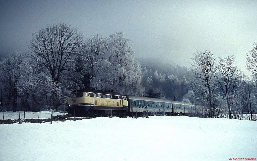 Eine unbekannte 218 verläßt an einem Dezembermorgen 1991 mit ihrem Zug nach München den Haltepunkt Osterhofen. Die Sonne hatte sich an diesem Tag noch nicht gegen den zähen Morgennebel durchsetzen können und machte dadurch das Foto mit den rauhreifbedeckten Bäumen möglich