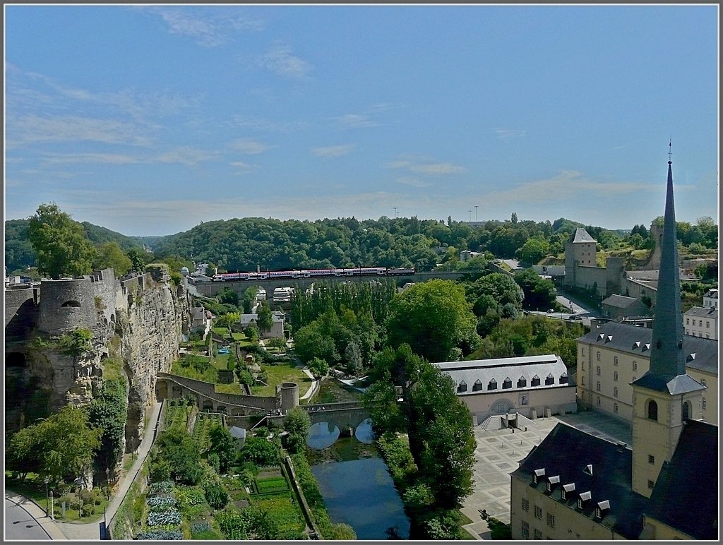 In Luxemburg ist nicht die Bahn Weltkulturerbe, sondern der historische Kern der Altstadt, sowie einige der erhaltenen Festungsbauten. 

Links im Bild sieht man den Bockfelsen, der auch als die Wiege Luxemburgs bezeichnet wird. Hier errichtete der Ardennergraf Siegfried im Jahre 963 eine Burg, die Lucilinburhuc, welche als Grundlage fr die sptere Stadtgrndung angesehen wird. 

Rechts ist die Abtei Neumnster zu sehen, welche von 1869-1984 als Gefngnis diente und heute ein Kulturzentrum bildet. Neben dem Turm der Kirche Sankt Johann ist eines der grten Tore, die Dinselpforte aus dem 15. Jahrhundert zu sehen. 

Der Fluss in der Mitte des Bildes ist die Alzette mit dem kleinen Steg  Stierchen  und einem von mehreren Trmchen, daneben erkennt man die  hngenden Grten , wo sogar Wein angebaut wird. 

Ach ja, ein Wendezug ist auch noch zu sehen, er berquert den Clausener Viadukt im Hintergrund. 01.08.09 (Jeanny)