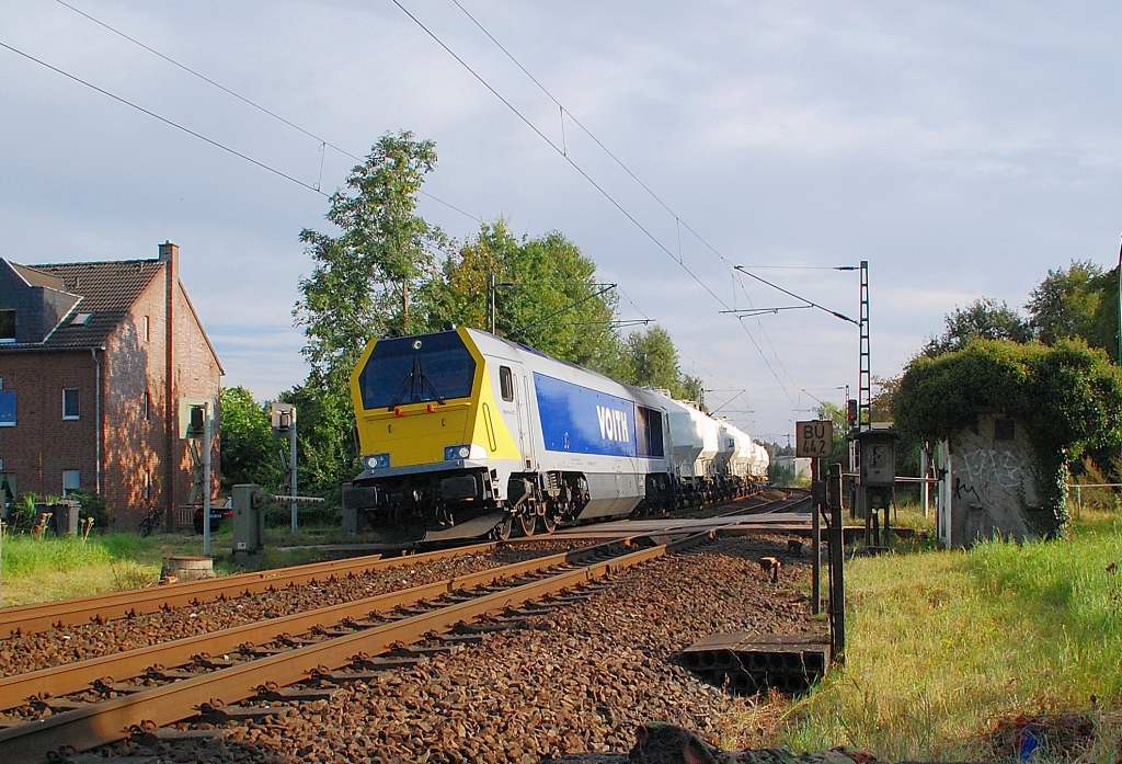 In Osterath am Bahnbergang Viehgasse fhrt gerade die Voith 264 001-9 am Sonntag den 2.9.2012 mit einem Zemetwagenzug durch den Gleisbogen in Richtung Krefeld.