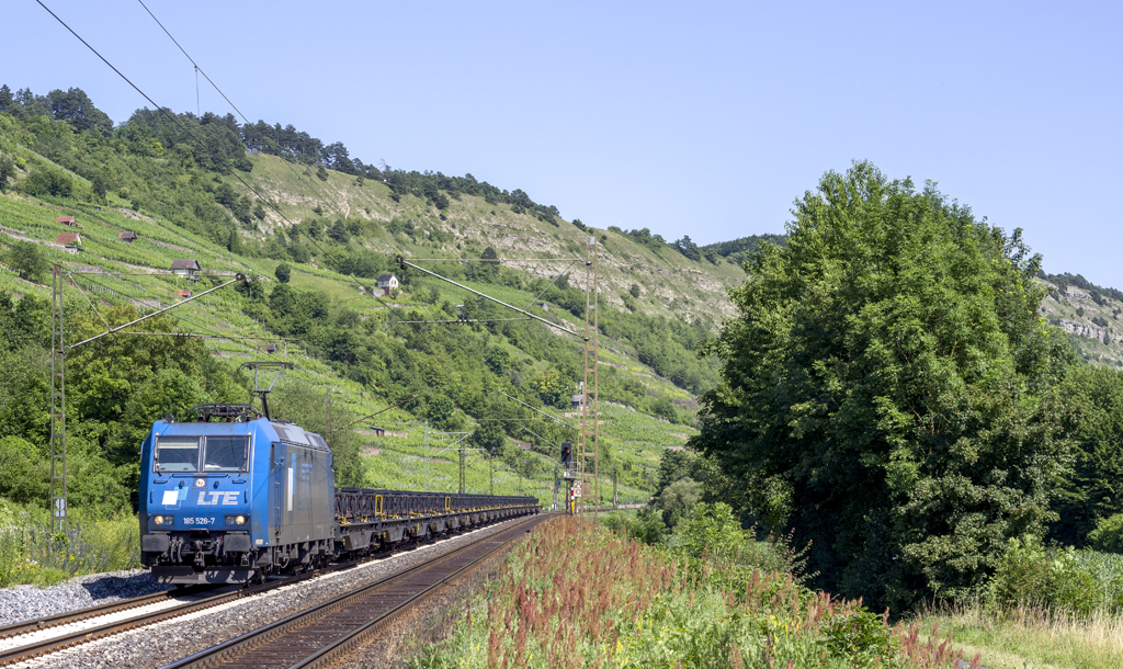 LTE 185 528-7 fhrt mit einem Flachwagenzug durch das Maintal, hier bei Harrbach (07.07.2013)