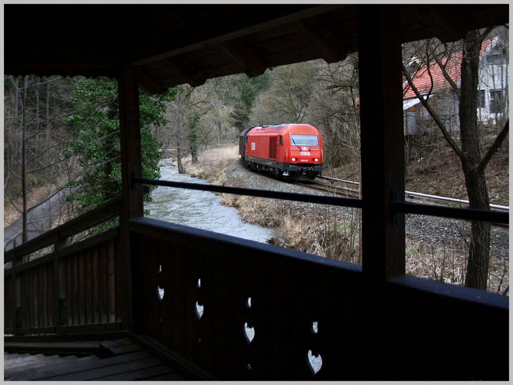 Moderne Nebenbahnromantik Gutensteiner Bahn: 2016 018 ist mit einem Gterzug zwischen Ortmann und Miesenbach unterwegs, beobachtet von diesem Holzweg ber der Piesting. 2.3.12