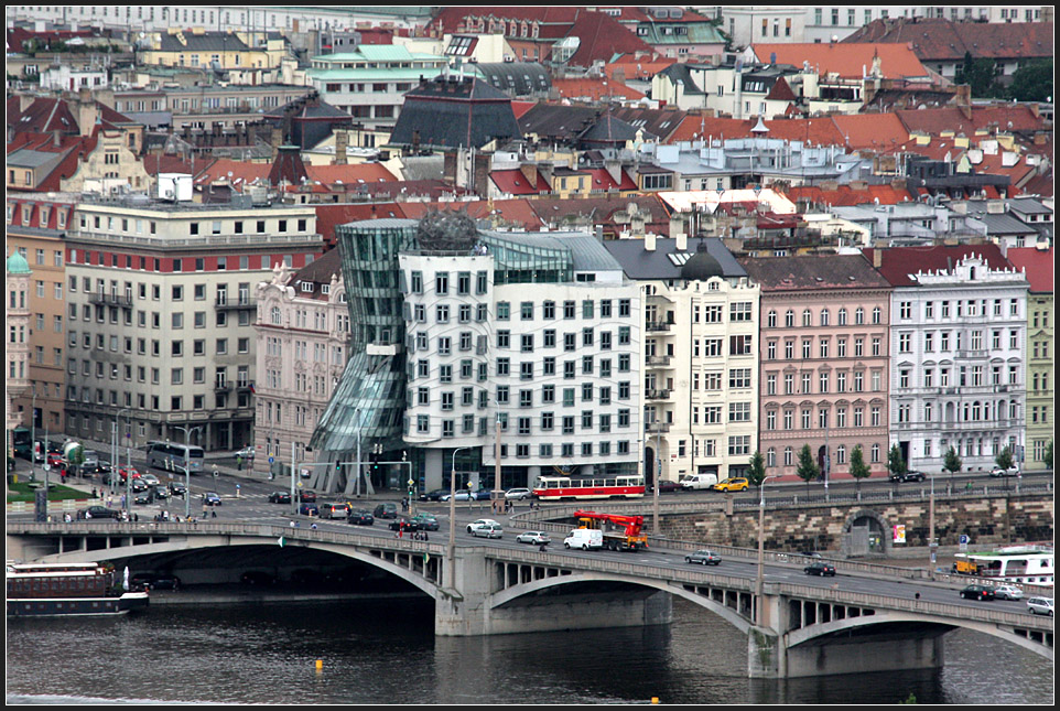 Obwohl nur sehr klein im Bild ist die als Einzelwagen fahrende Straßenbahn doch sehr leicht zu finden. Dahinter das moderne Wahrzeichen von Prag, das tanzende Gebäude von Frank Gehry. 14.08.2010 (Matthias)