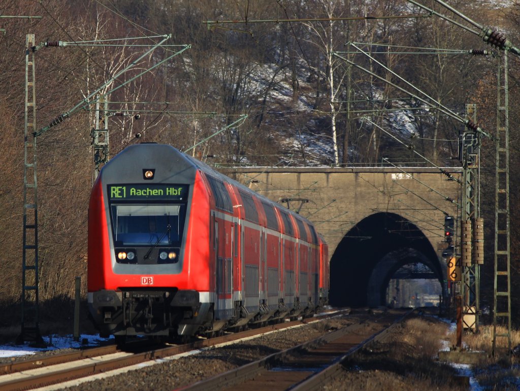 RE1 geschoben von 146 004-7 hat am 11.02.2012 Stolberg Hbf verlassen, den Nirmer (125 m) und den Eilendorfer Tunnel (357 m) durchfahren und fhrt nun durch Eilendorf zum nchsten Halt Aachen Rothe Erde. 
