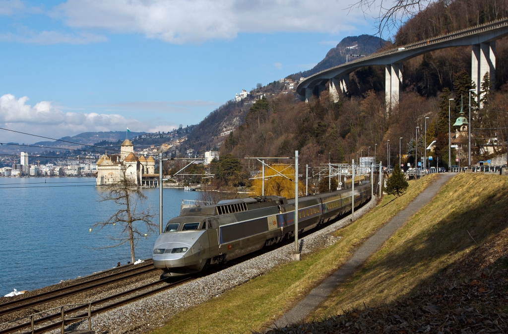 TGV Lyria (112) der Verbindung Paris–Dijon–Lausanne–Brig bediehnt, er fhrt hier am 26.02.2012 bei  Clos du Moulin am Genfersee Richtung Brig entlang, hinten Chteau de Chillon, dahinter Montreux.