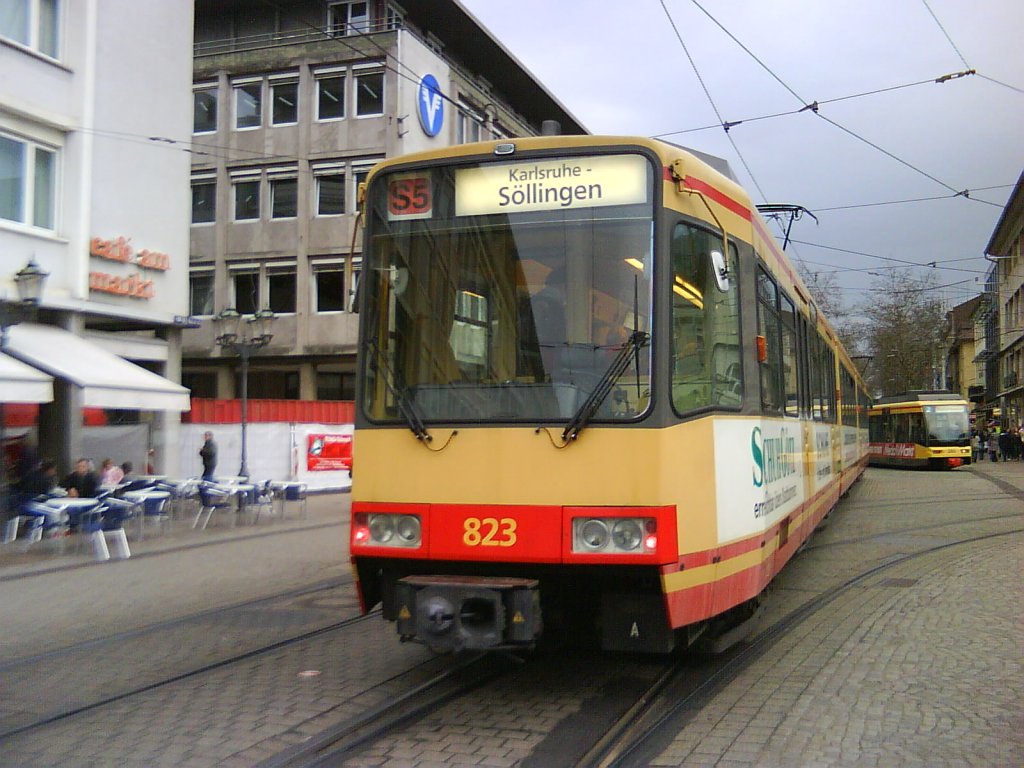 Tw 823 (von hinten gesehen) als S5 nach Karlsruhe-Sllingen auf dem Karlsruher Marktplatz. Dahinter befindet sich Tw 2?? als Tram 2 nach Wolfartsweier. Die Aufnahme entstand am 20.03.2010.