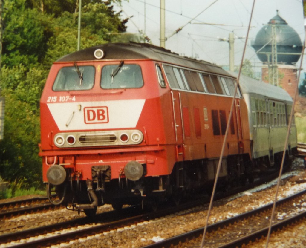 Vor Elektrifizierung der Murrbahn waren Maschinen der Baureihe 215 Stammgste in Crailsheim. 215 107-4 beschleunigt im Februar 1997 ihren Regionalexpress aus der westlichen Bahnhofsausfahrt heraus. Im Hintergrund der Crailsheimer Wasserturm - eines der wenigen berbleibsel des einstmalig bedeutenden Bws (digitalisiertes Dia).