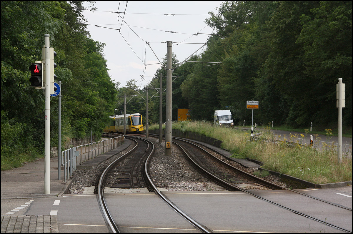 . Die früher Haltestelle entfiel -

An dieser Stelle am östlichen Ortsrand von Stuttgart-Weilimdorf befand sich vor dem Stadtbahn-Ausbau die Haltestelle Föhrichstraße/Schützenhaus, wie die Aufnahme von Kurt zeigt:

http://www.bahnbilder.de/bild/deutschland~strassenbahn~stuttgart-keine-stadtbahn/672284/stuttgart-ssb-sl-6-gt4-728.html

Im Zuge des Ausbaus und um im Tunnelbereich eine zweite Station zu vermeiden wurden die Haltestelle an dieser Stelle und an der Mathildenstraße zu einer neuen Haltestelle Landau Straße zusammengelegt. Wobei man sagen muss die Haltestelle Föhrichstraße/Schützenhaus lag schon außerhalb der Bebauung und der Abstand zur Haltestelle Mathildenstraße war recht groß, so dass sich insgesamt die Erschließung durch die Bahn nicht zu sehr verschlechtert hat.

Hier habe ich einen etwas anderen Standort gewählt als auf dem Bild von Kurt, da ich weder die Straßen neben den Fußgängerampeln noch die Gleise außerhalb des Überweges überqueren wollte. Aber man kann dennoch die Veränderungen sehen.

26.07.2016 (M)

