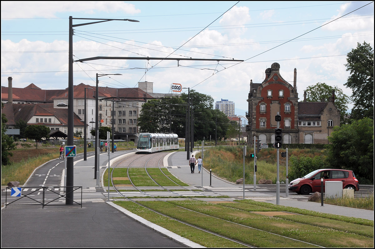 . Straßenunabhängig - 

...führt die neue Trasse der Tram Linie D in Straßburg durch das früherer Hafengebiet. Parallel wurde ein Fuß- und Radweg angelegt. Die im Bild sichtbare Haltstelle 'Starcoop' wird noch ohne Halt durchfahren.

25.06.2017 (J)