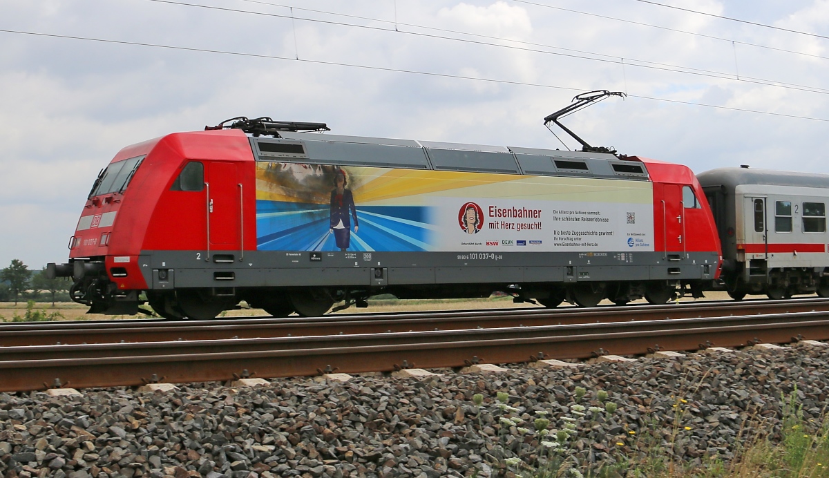101 037-0, mit der etwas lädierten Werbung für Eisenbahner mit Herz, zieht einen IC aus Richtung Hannover Hbf kommend. Aufgenommen am 29.07.2015 in Dedensen-Gümmer.