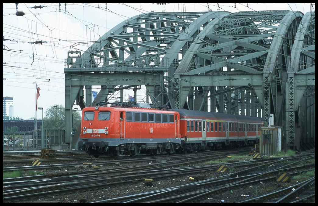 110207 verlässt am 9.5.2001 um 14.21 Uhr mit dem RE nach Koblenz die Hohenzollernbrücke in Köln und fährt in den HBF Köln ein.