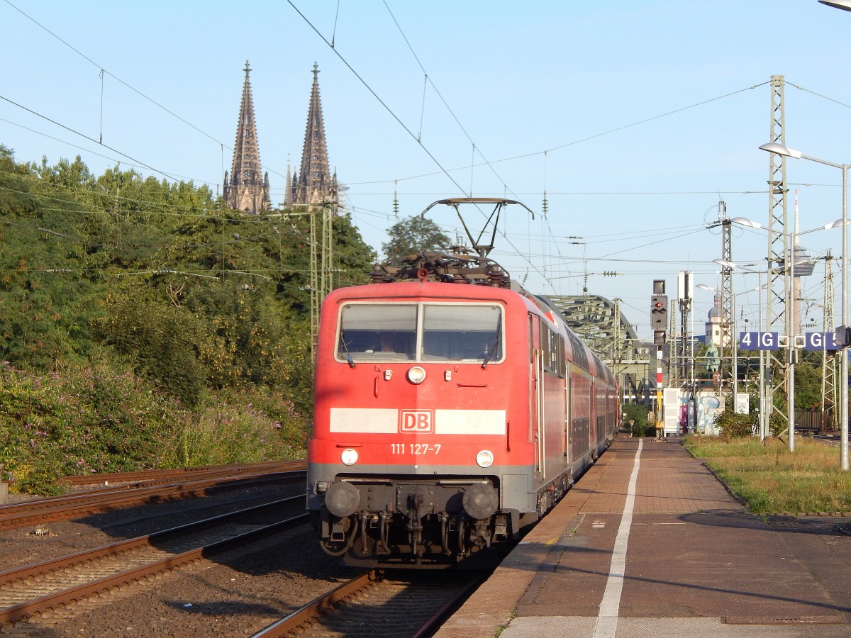 111 127 kommt mit einem RE vor dem Dom Türmen am Morgen des 1.8 in Köln Deutz eingefahren.

Köln Deutz 01.08.2015