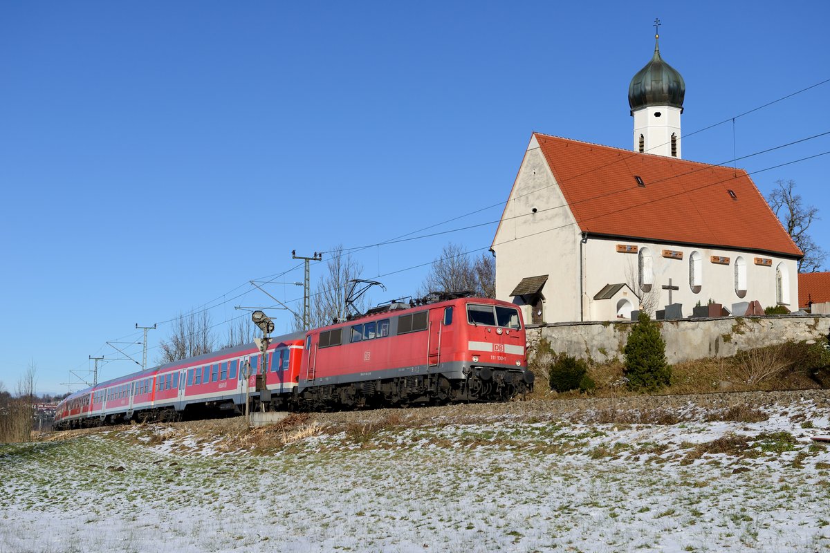 111 130 konnte am 08. Dezember 2013 vor der RB 59521 im Murnauer Moos abgelichtet werden. Im Hintergrund die barocke Filialkirche St. Georg aus dem 17. Jahrhundert.