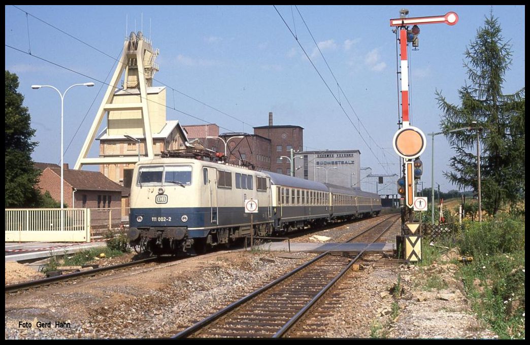111002 mit E 3052 nach Heilbronn am 15.8.1989 um 11.23 Uhr vor der Kulisse des Salzbergwerks in Bad Friedrichshall Kochendorf.