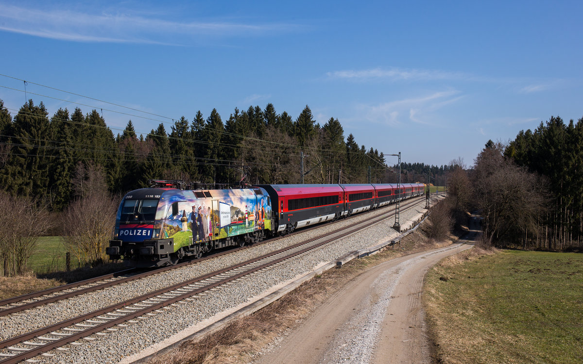 1116 157 fährt mit einem Railjet bei Grabenstätt in Richtung Rosenheim, aufgenommen am 25. März 2018.