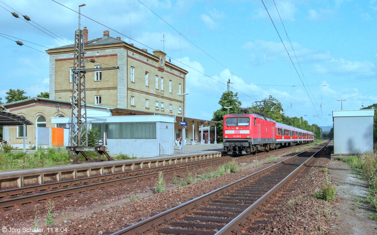 112 162 hielt am 11.8.04 mit einer RB nach Würzburg in Marktbreit. Die Unterführung am rechten Bildrand führte nur noch zum Gleis 3, südlich davon war der Bahnkörper leergeräumt. Nur Fotografen freuten sich darüber, dass dies neue Perspektiven erlaubte.