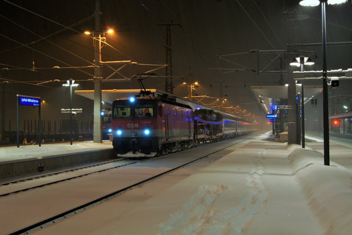 1144 057 der ÖBB mit EN 40465 (Zürich-Zagreb mit Kurswagen nach Beograd) am frühen Morgen des 12.02.2018 beim Halt im Bahnhof Spittal-Millstättersee. Trotz heftigen Schneefalls ist der Zug auf die Minute pünktlich.