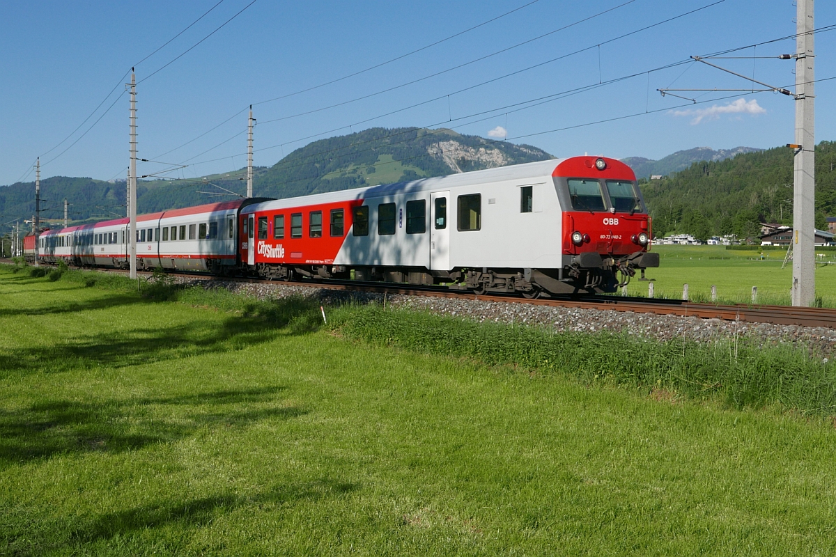 1144 115 schiebt am 27.05.2017 den IC 518, Graz - Innsbruck, mit Steuerwagen 80-73 040-2 an dem in der Nähe von St. Johann in Tirol stehenden Fotograf vorbei.