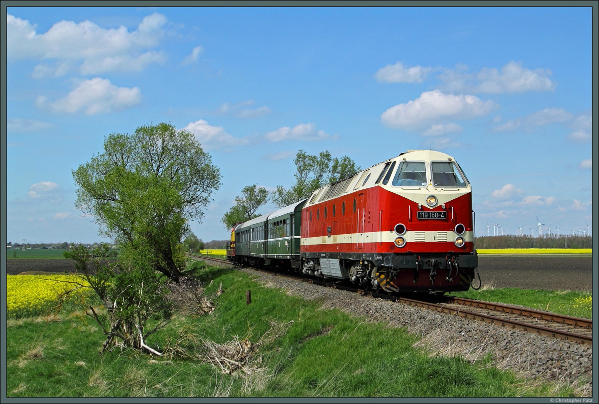 119 158-4 hat mit dem Rekowagenzug P 9008 die Stadt Egeln verlassen und durchfährt auf dem Weg nach Schneidlingen nun die blühenden Rapsfelder. Am Zugschluss läuft V 90 002 der AVG mit. (02.05.2015)