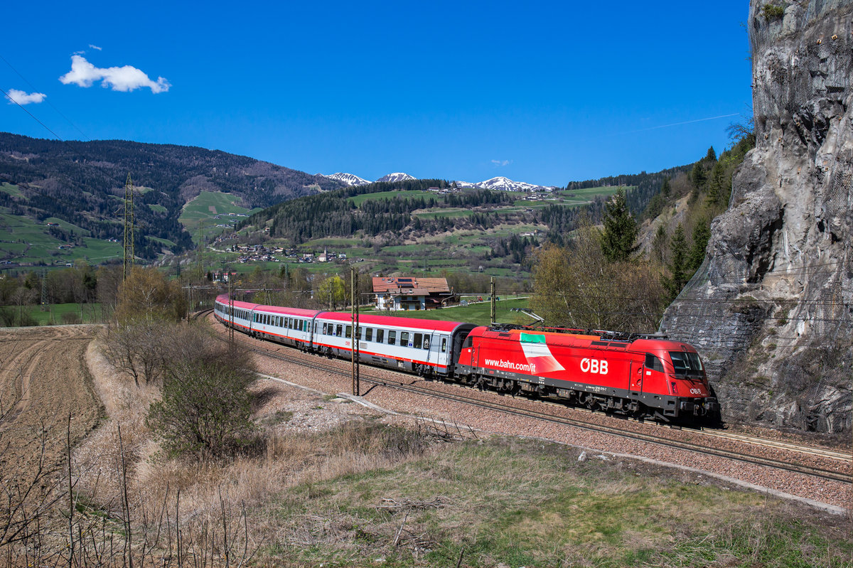1216 011 fährt mit einem Eurocity an der bekannten Felswand bei Vipiteno in Richtung Bozen, aufgenommen am 8. April 2017.