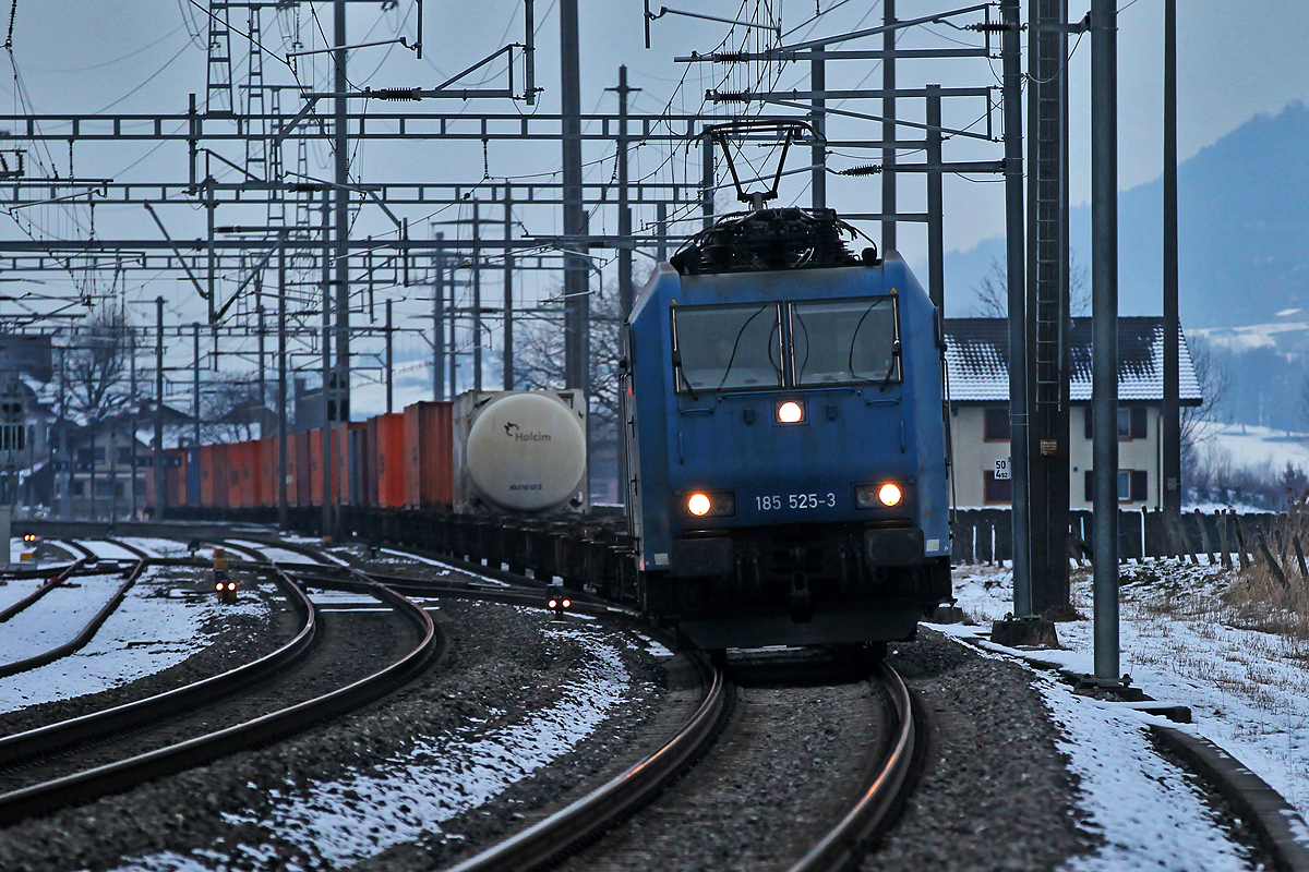 185 525-3,die an die BLS vermietet ist,kommt beim Einnachten mit einem Containerzug in Reichenburg vorübergefahren.Bild vom 20.1.2015