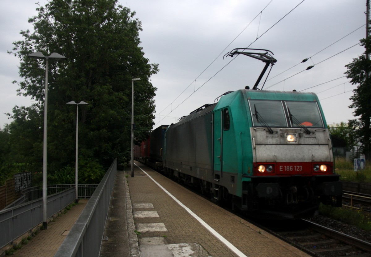 186 123 von Railtraxx kommt als Umleiter mit einem langen KLV-Containerzug aus Frankfurt-Höchstadt am Main(D) nach Genk-Goederen(B) und kommt durch Kohlscheid aus Richtung Herzogenrath und fährt die Kohlscheider-Rampe hoch nach Aachen-West. 
Bei Regenwetter am Abend vom 26.7.2015.