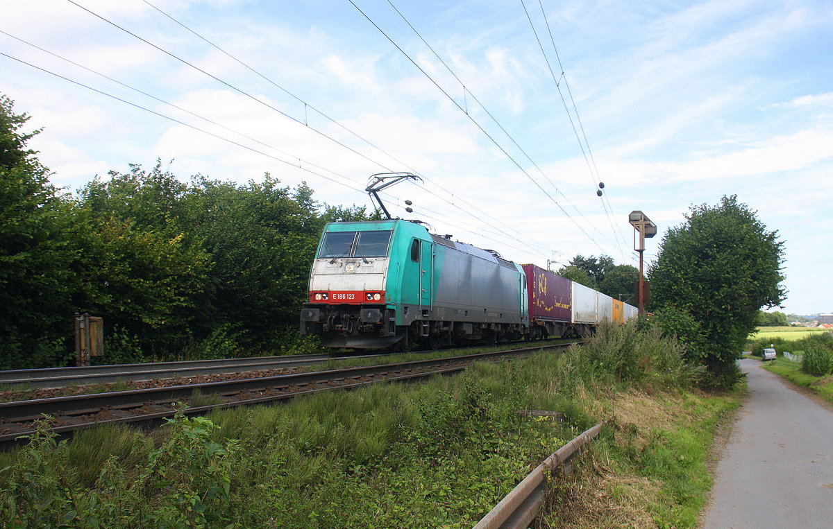 186 123 von Railtraxx kommt aus Richtung Aachen-West und fährt die Gemmenicher-Rampe hoch mit einem langen KLV-Containerzug aus Frankfurt-Höchstadt am Main(D) nach Genk-Goederen(B). Aufgenommen an der Montzenroute am Gemmenicher-Weg. Bei Sommerwetter am Nachmittag vom 7.8.2016.