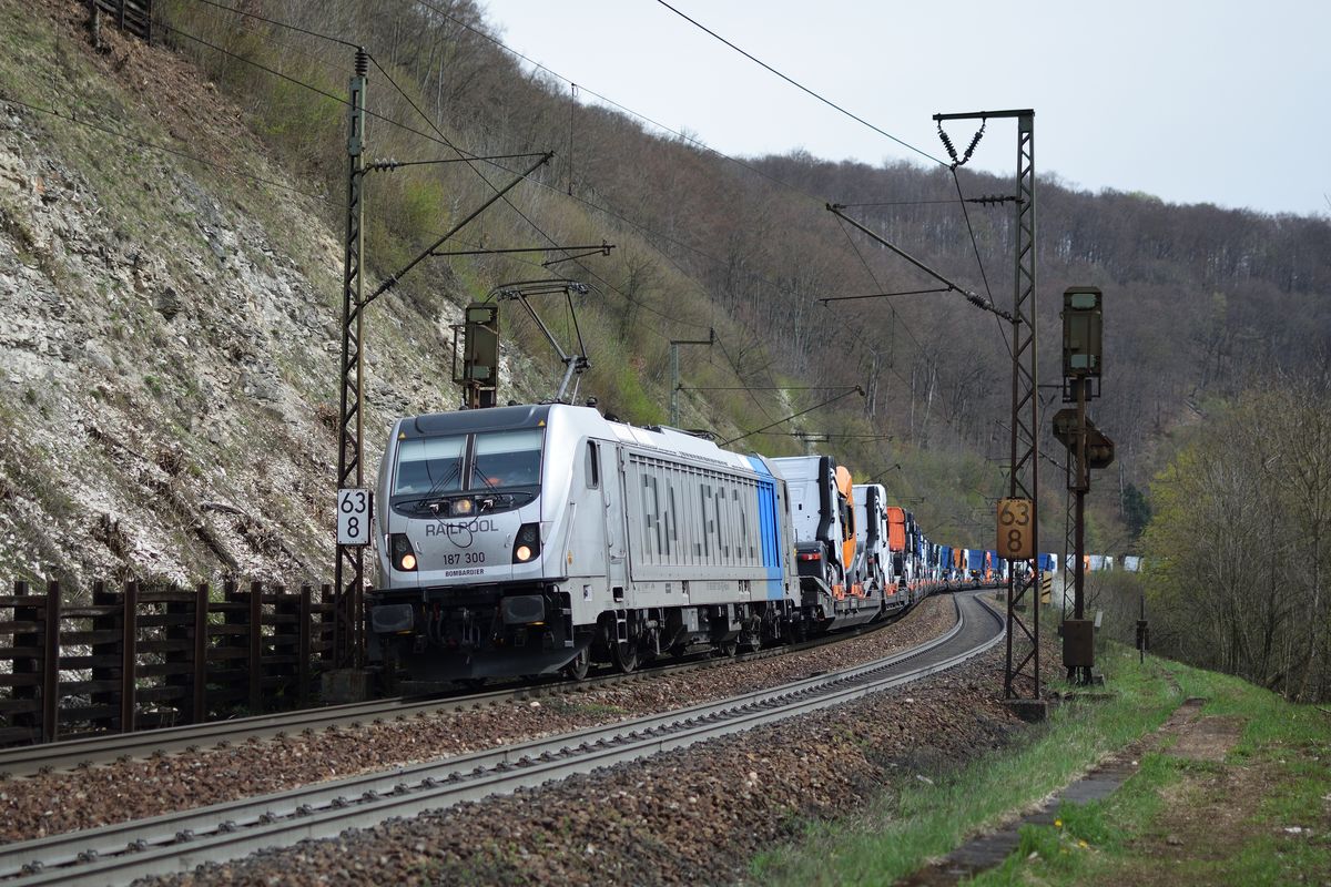 187 300 von Railpool zieht am 15. April 2018 einen mit Lkws beladenen Güterzug die Geislinger Steige hinunter.