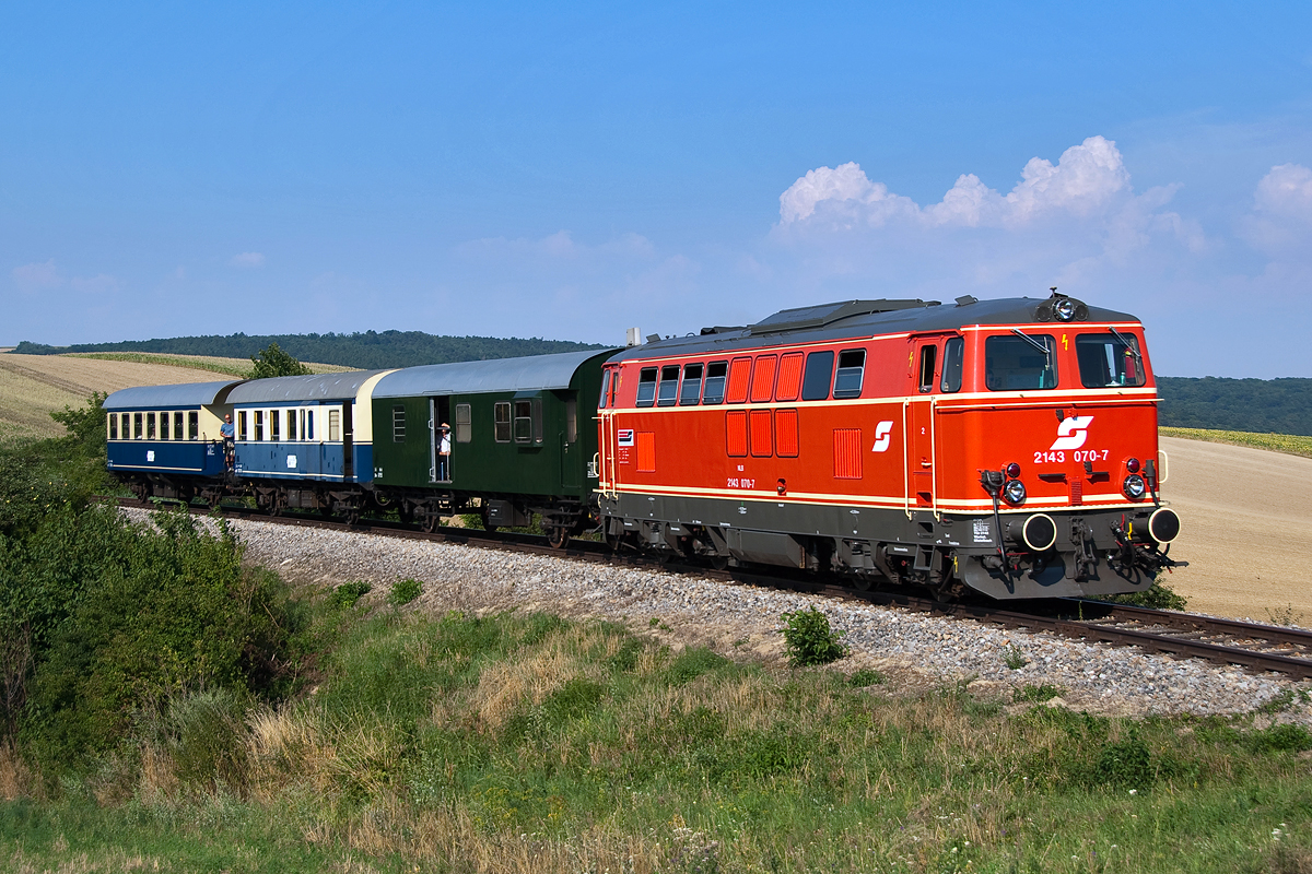 2143 070, war am 08.08.2015, an einem extrem heißen Sommernachmittag mit dem Nostalgie Express  Leiser Berge  von Ernstbrunn nach Wien Praterstern unterwegs. Diese Aufnahme entstand kurz vor Würnitz-Hetzmannsdorf.