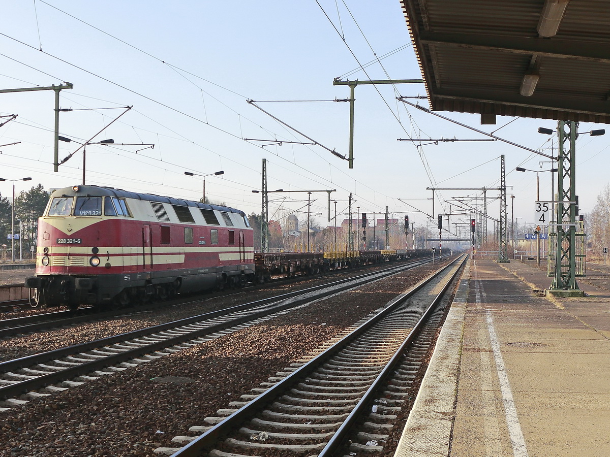228 321-6 der Cargo Logistik Rail Service GmbH passiert den Bahnhof Berlin Schönefeld Flughafen am 06. Februar 2019 mit einem Zug leerer Schotterwagen.