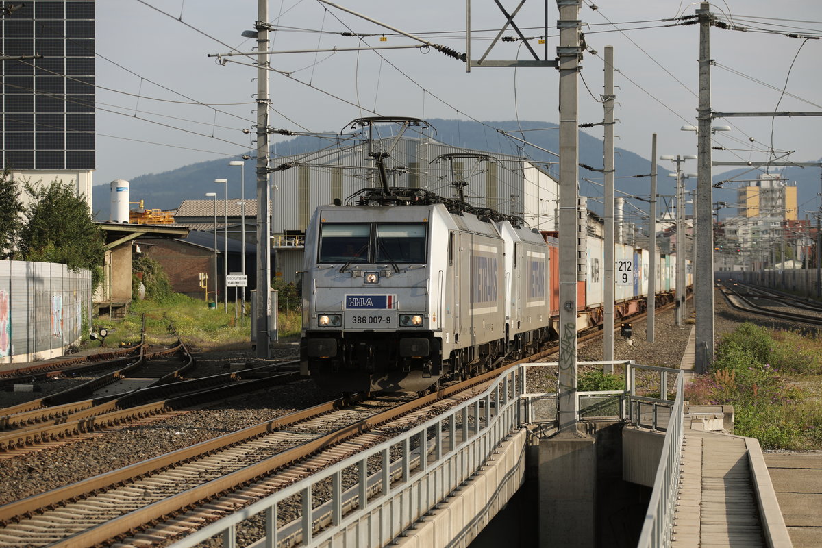 386.007 führt einen Containerzug an der durch Graz Hauptbahnhof donnert. 
Hier in Don Bosco am 25.August 2017