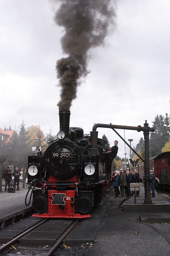 99 5901 am Nachmittag des 18.10.2013 beim Wasserfassen im Bahnhof Drei Annen Hohne. Wie die Rauchfahne der Lok zeigt, sind fr die unmittelbar bevorstehende Bergfahrt zum Brocken, heute mit einem Sonderzug der IG HSB, noch ein paar Schippen Kohle aufgelegt worden. Die Reisenden des Zuges nutzen derweil die willkommene Pause fr einen kleinen Snack am  Suppenwagen . Der auf Gleis 2 stehende Zug ist soeben vom Brocken gekommen und wird als P8923 um 15.06 Uhr dorthin zurckfahren.