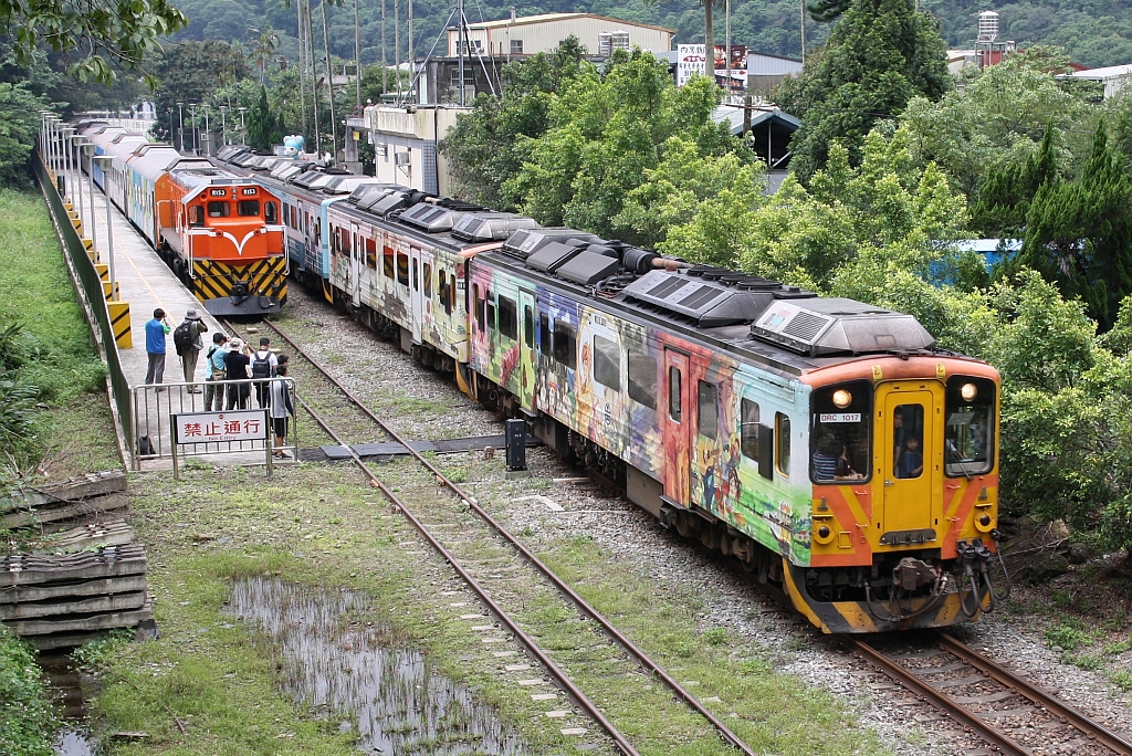 Am 10.Juni 2017 wartet in der Neiwan Station die R153 (Co'Co'-de, GM-EMD, Type G22CU, Bauj. 1973, Fabr.Nr. 712757) mit einem Sonderzug auf die Rückkehr der Passagiere während der DRC1017 als Local Train 1815 nach Zhuzhong Station ausfährt.