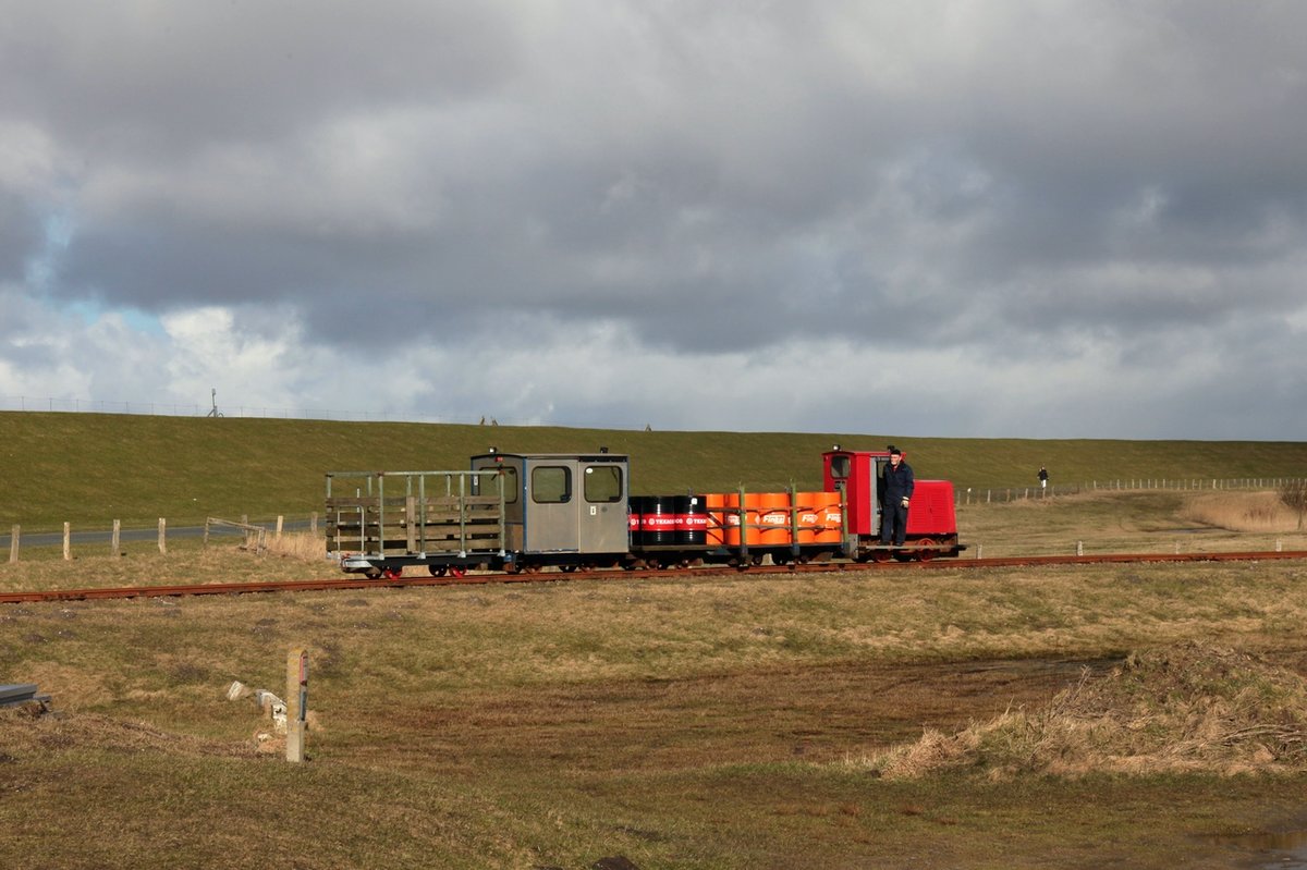 Am 24.02.2016 schiebt die private Schöma 2570 ihren Zug am Lüttmoorsiel zum Deich. An erster Stelle eine Schafskiste, die für weitere Einsätze fit gemacht wurde, dann folgt Lore 1 und danach 2 Flachwagen mit Fässern gefüllt mit Heizöl.