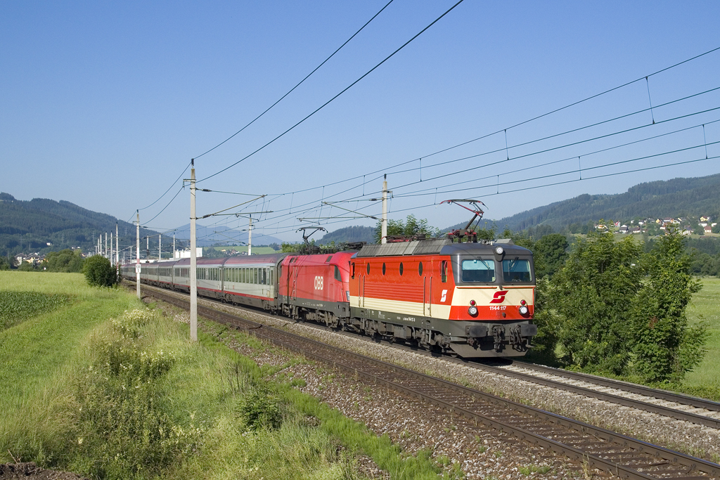 Am 29. Juni 2016 war 1144 117 gemeinsam mit 1116 169 am EuroNight 234 (Roma Termini - Villach - Wien Hauptbahnhof) unterwegs. Bei bester Morgensonne konnte der Zug bei Freßnitz zwischen den Bahnhöfen Mitterdorf-Veitsch und Krieglach fotografiert werden.