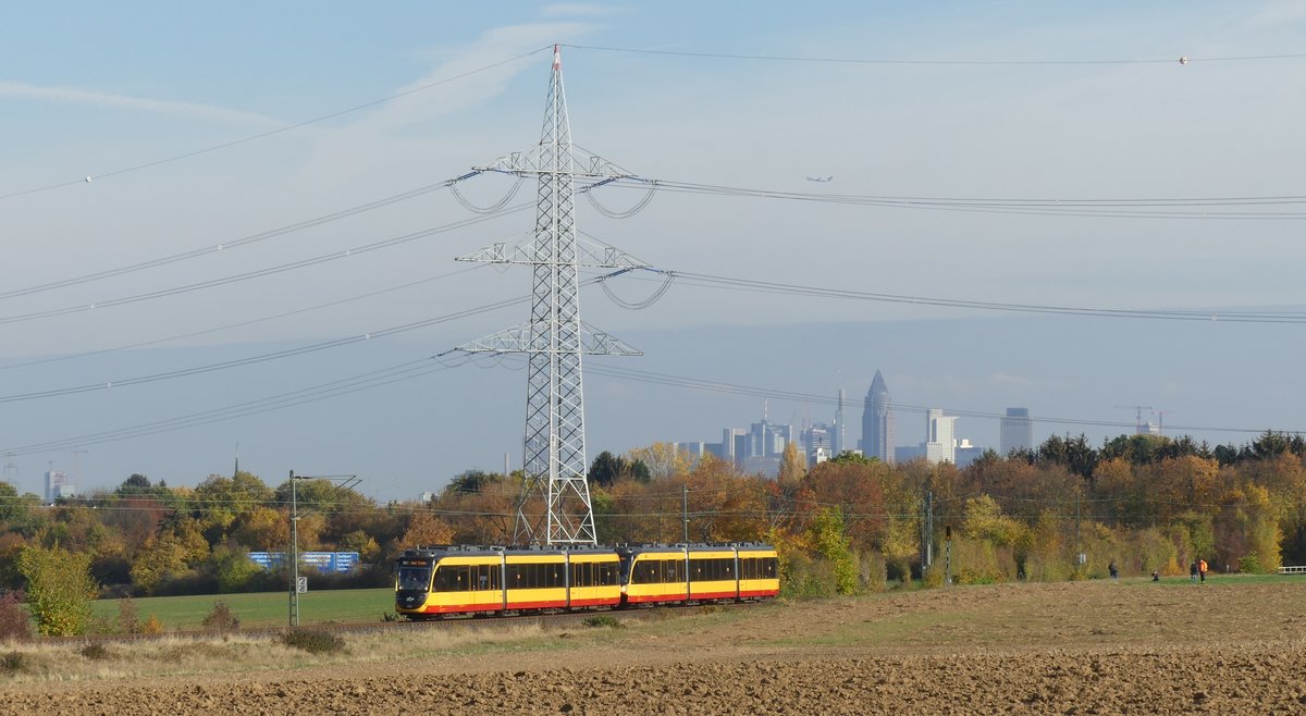 Am 3. November 2018 fanden auf der RB11 Frankfurt Höchst - Bad Soden Vorführungsfahrten mit einem AVG-Stadtbahntriebwagen statt. Damit sollte für das Projekt  Regionaltangente West , eine geplante Stadtbahnstrecke westlich von Frankfurt, geworben werden. Hier präsentieren sich die beiden Triebwagen auf dem Weg nach Bad Soden zwischen Frankfurt Sossenheim und Sulzbach (Taunus) vor den Türmen der Frankfurter Skyline. Aufgenommen am 3.11.2018 15:05