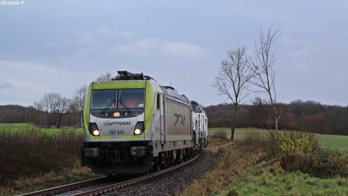 Am 9.12.17 überführte Vossloh-Locomotives aus Kiel-Friedrichsort fünf Brand Diesel-Elektrische loks des Typ DE18 und eine MaK DE2700. 
Hier erricht die 187 012 grade den Bü Lummerbruch in Altenholz, und damit das Ende der Brems-Teststrecke und gleichzeitig den Anfang der Last-Fahrten Teststrecke
Die Reihnfolge des DbZ 79865 :
91 80 6 187 012-0 D-CTD
5502221 (Weiß)(Noch keine NVR-Nummer vorhanden)
5502225 (Weiß)(Noch keine NVR-Nummer vorhanden)
5502224 (Weiß)(Noch keine NVR-Nummer vorhanden)
5502253 (Grün-Weiß)(Noch keine NVR-Nummer vorhanden)
92 80 1 251 009-7 D-VL
Diese Zugbildung wurde Allerdings nur bis Kiel-Suchsdorf gefahren, da sich dort das neue Vossloh-Locomotives Werk befindet, da 3 DE18 noch nicht Betriebsfähig sind, mussten sie dort Zurück gelassen werden.
Ab dem 31.12.17 ist das alte Werksgelände der Vossloh-Locomotives GmbH Leerstehend.
Für die 13,3km lange Strecke mit der Streckennummer 9104 (Neuwittenbek - Kiel-Friedrichsort - Vossloh) benötigte der DbZ 79865 105min, da nur V/Max 25 Km/h auf der Seehafen-Kiel eigenen Strecke Zugelassen sind (Mit Ausnahmegenehmigung bis zu 100 Km/h für Testfahrten).
Der von der Captrain Deutschland GmbH 187 012 angeführten Lokzug hatte ein Gesammtgewicht von 537t aufgeteilt auf 100m Zuglänge und 26 Achsen.