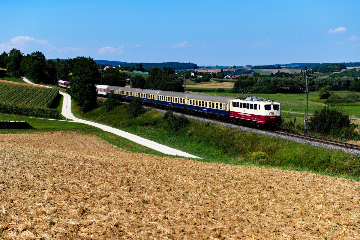 Am Abend des 31. Juli 2018 startete am Münchner Ostbahnhof ein Sonderzug zum bekannten Heavy Metal Festival in Wacken. Dieser wurde von Euro Express angeboten. Der Leerpersonenzug musste zugeführt werden und sollte dabei interessanterweise den Weg über die Riesbahn nehmen. So wurde bei Wörnitzstein Position bezogen und in großer Hitze der Dinge geharrt, die da kommen sollten. Relativ bald erschien dann auch schon die in TEE-farben gehaltene 110 169 mit ihrem 15-Wagen-Zug. Dieser war vom Wagenpark her bunt zusammengewürfelt, am Zugschluss befand sich sogar ein Schlafwagen der Gattung AB30. Eine schöne Abwechslung auf der sonst so ruhigen Strecke. 