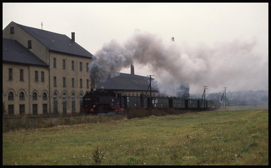 Am Stadtrand von Zittau dampft hier am 7.10.1992 die 99725 mit ihrem Personenzug Richtung Bertsdorf an einem alten Fabrikgebäude vorbei.