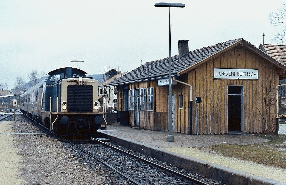 An einem regnerischen Apriltag 1988 fährt 211 322-3 im Bahnhof Langenneufnach (Strecke Gessertshausen - Markt Wald) ein. Am 31.05.1991 verkehrte hier der letzte Personenzug. Heute gehört die Strecke der Staudenbahn, die eine Wiederaufnahme des regulären Personenverkehrs beabsichtigt.