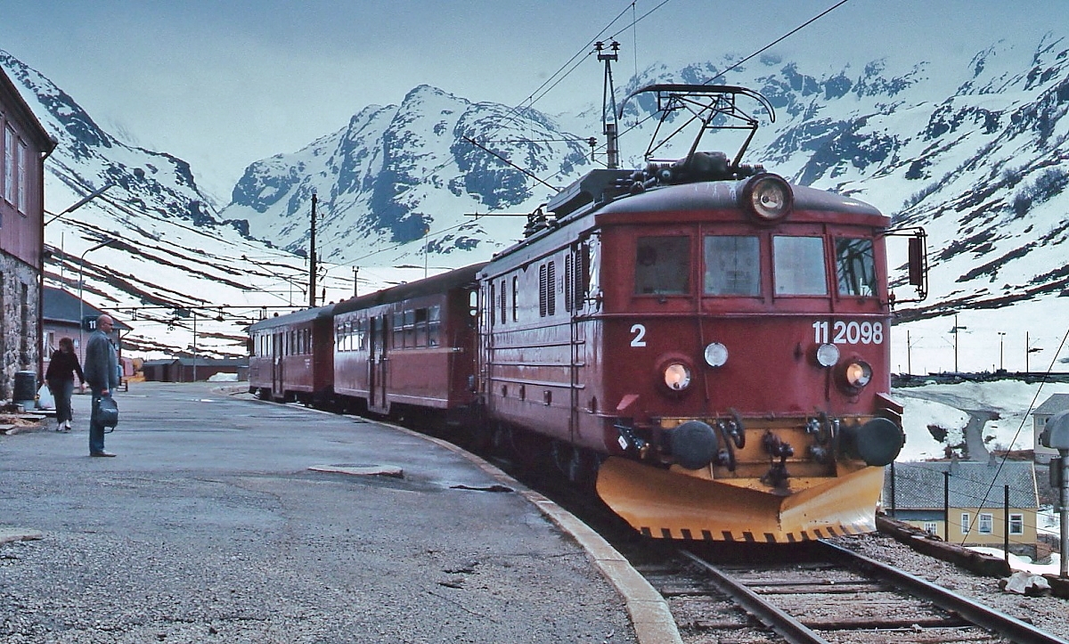 Anfang Mai 1988 steht El 11.2098 der NSB abfahrbereit nach Flam im Bahnhof Myrdal der Bergenbahn. Zwischen den beiden Bahnhöfen überwindet die Flambahn auf rund 20 km einen Höhenunterschied von 864 m bei einem maximalen Gefälle von 55 Promille, sie gehört damit zu den steilsten normalspurigen Adhäsionsbahnen der Welt. Die El 11.2098 wurde 1954 in Dienst gestellt und 1997 ausgemustert. Für den Einsatz auf der Flambahn erhielt sie zusammen mit zwei weiteren El 11 eine geänderte Getriebeübersetzung.