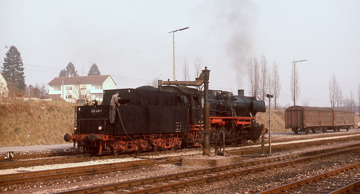 Anscheinend ist der Wasserkran im Bahnhof Ehingen im Dezember 1975 nur noch Dekoration, denn zum Wasserfassen nutzt der Heizer der Ulmer 050 419-1 den Schlauch