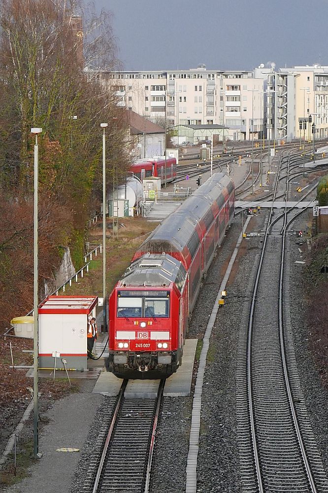 Auf Grund von Gleisbauarbeiten zwischen Friedrichshafen und Kressbronn vom 19.02. bis 25.03.2018 endete die Fahrt der RE-Züge von Stuttgart nach Lindau vorzeitig in Friedrichshafen. Der dadurch verlängerte Aufenthalt in Friedrichshafen wurde genutzt, um die Loks zu betanken. Am 12.03.2018 steht 245 007 mit den Wagen des ex RE 4223 nach einem kurzen aber heftigen Regenschauer an der Friedrichshafener Tankstelle.