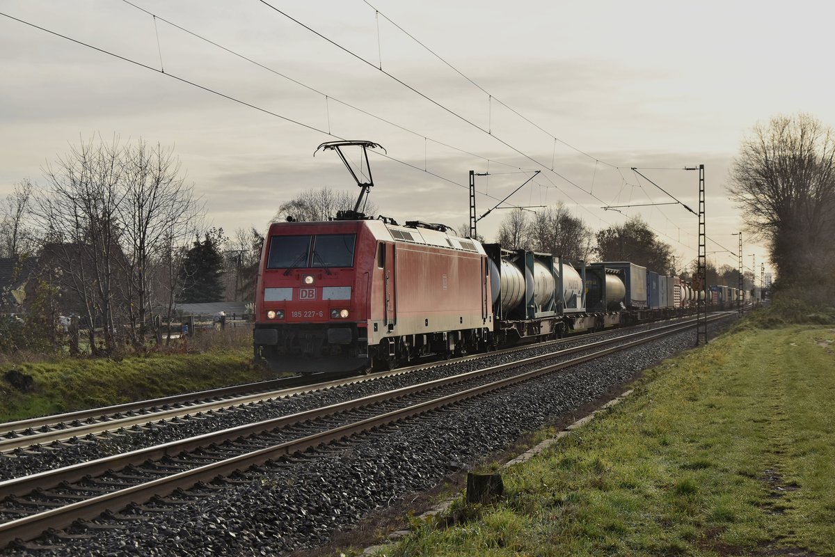 Aus dem Gegenlicht kommt die 185 227-6 mit einem Kastelzug aus Richtung Weissenberg gen Osterath gefahren am Morgen des 1. Dezember Zweitausendachtzehn, hier ist der Zug bei Kaarst Broicherseite.
