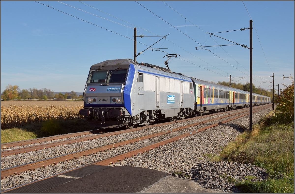 Bahn im Elsass. Die schmucke silberne Sybic 26147 zieht einen TER von Basel Richtung Mlhausen am Flughafen Basel/Mlhausen vorbei. Bartenheim, Oktober 2017.